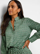 Green, cream, and black abstract dot print long-sleeve button-down top.
