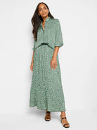 Pleated maxi skirt in green, black, and white abstract dot print.