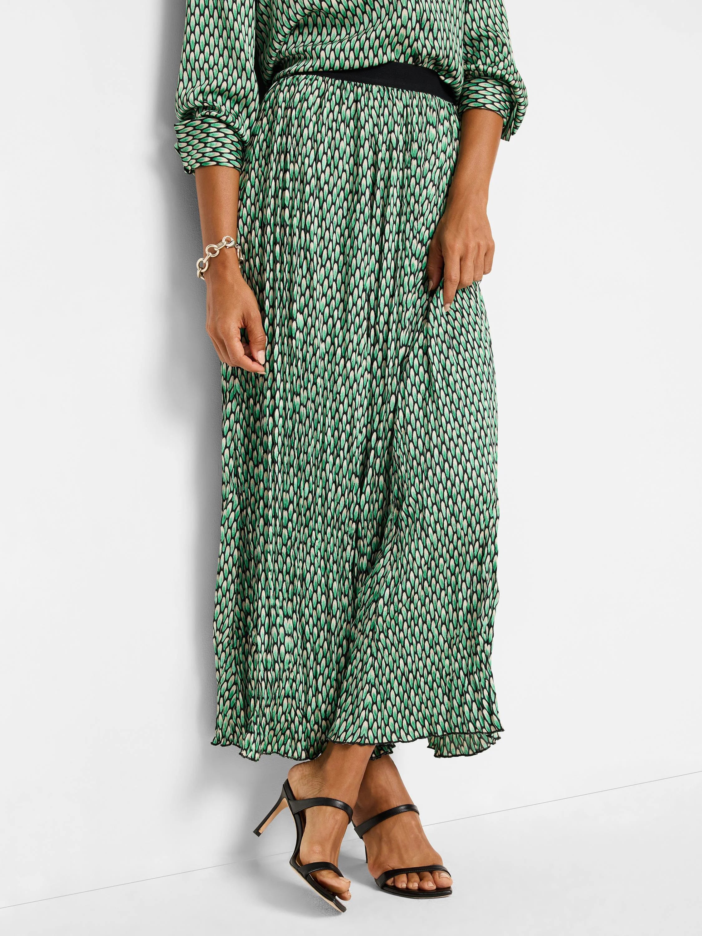 Green, black, and cream pleated maxi skirt with abstract dot pattern.