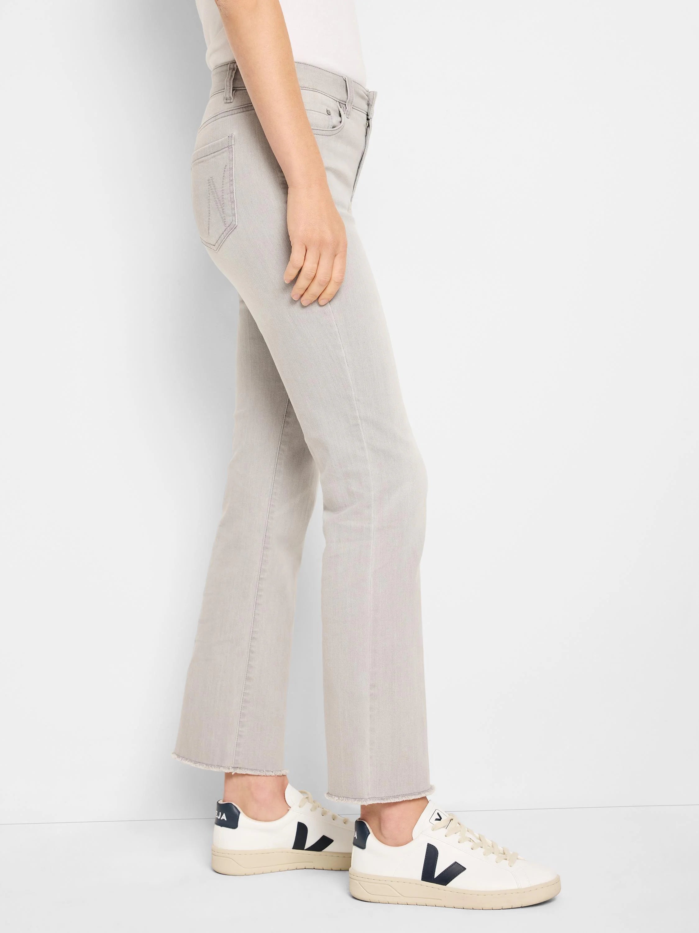 Light grey mid-rise jeans with a slim thigh, subtle bootcut leg, and frayed raw hems.