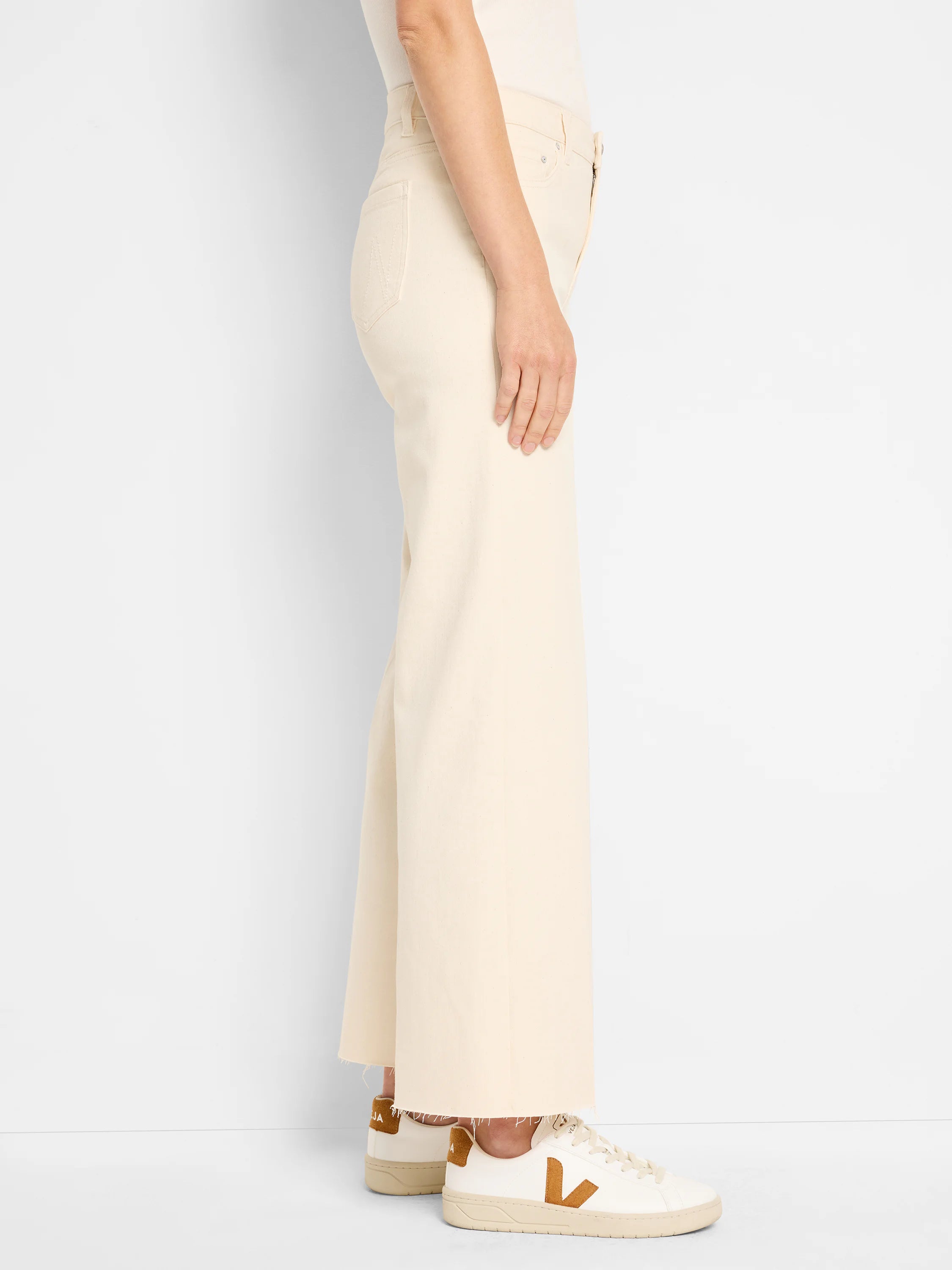 Ecru wide leg jeans with a frayed hem, shown worn from the side.