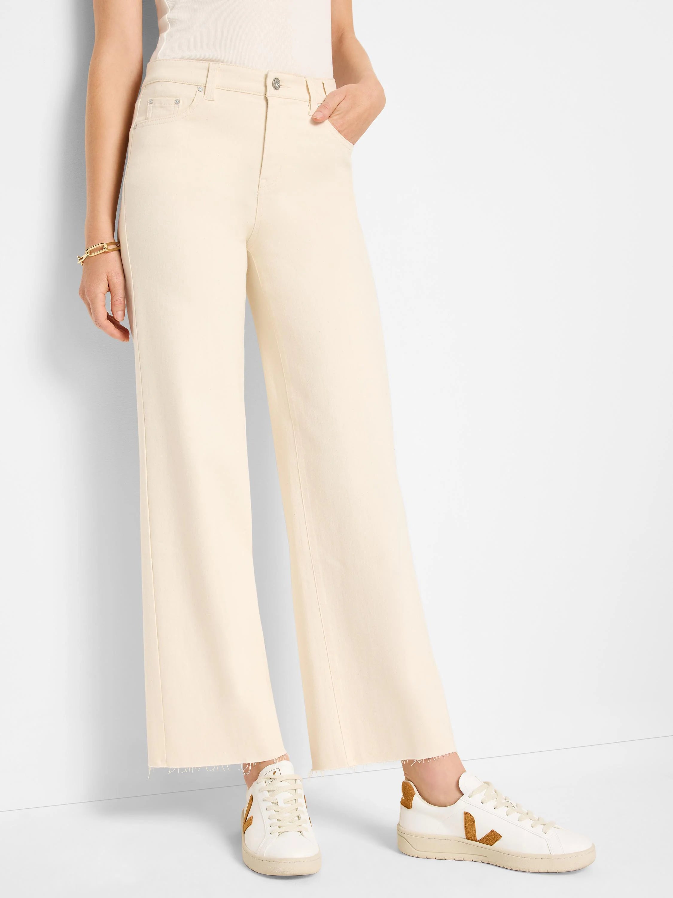 Ecru wide-leg jeans with front pockets, a button, and frayed ankle hems.
