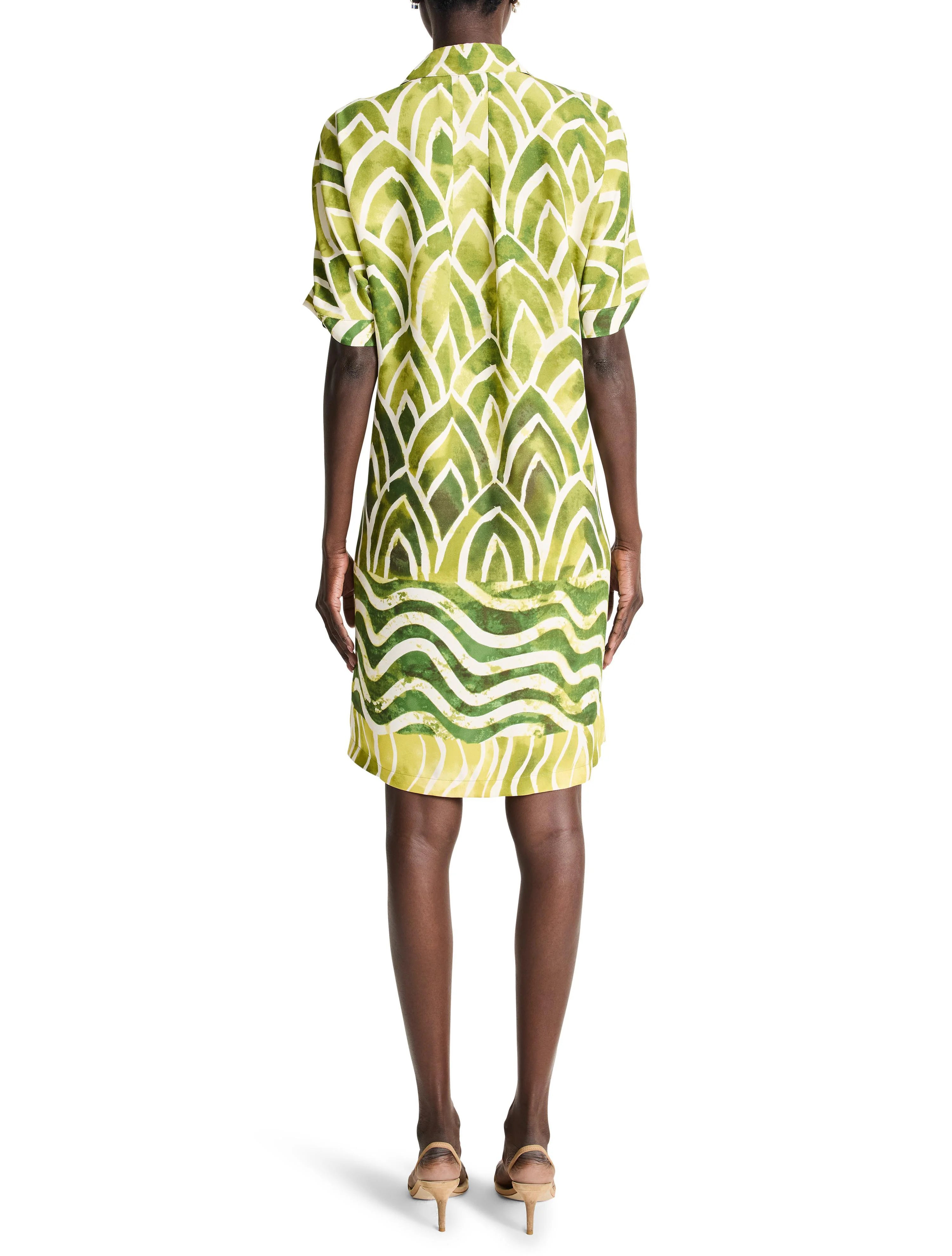 Green & yellow leaf-print short-sleeved shirt dress.  Waves at hem.  Back view.