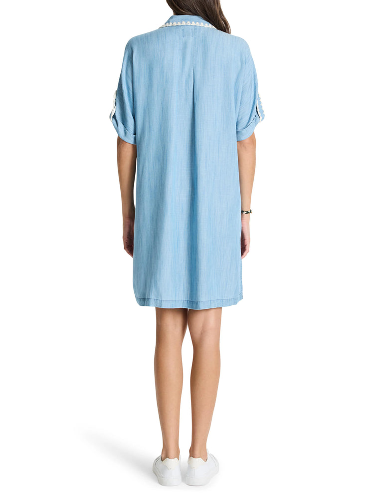 Light blue denim shirt dress, short sleeves, off-white collar trim.  Back view.