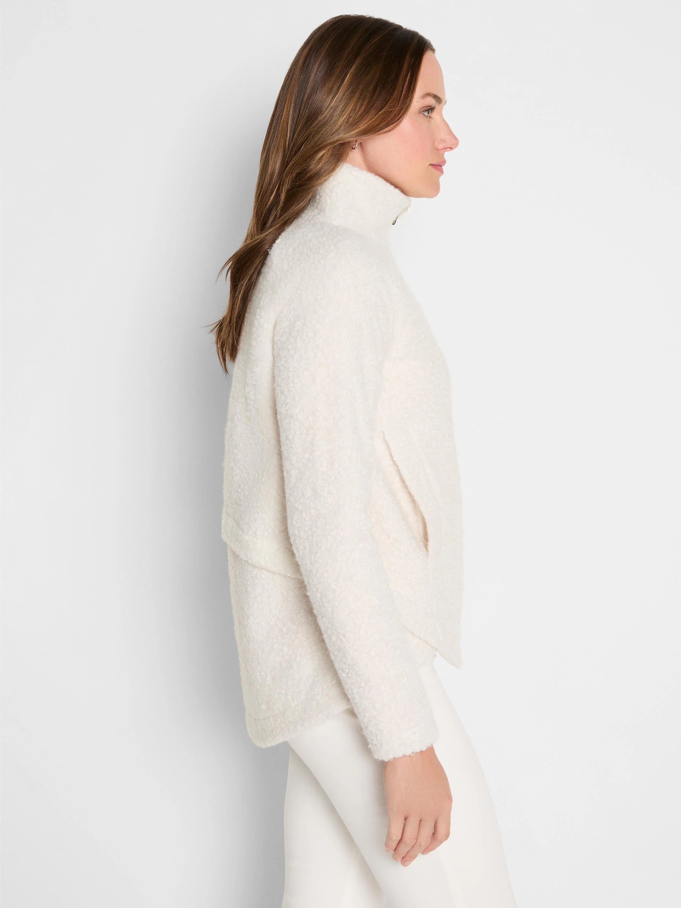 Cream curly boucle jacket with high neck, front zipper, and side pockets.