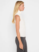 Cream ribbed sleeveless turtleneck tank, worn by a woman in profile.