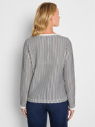 A fitted black and white vertical patterned long sleeve knit top features solid white trim at the neckline and cuffs.