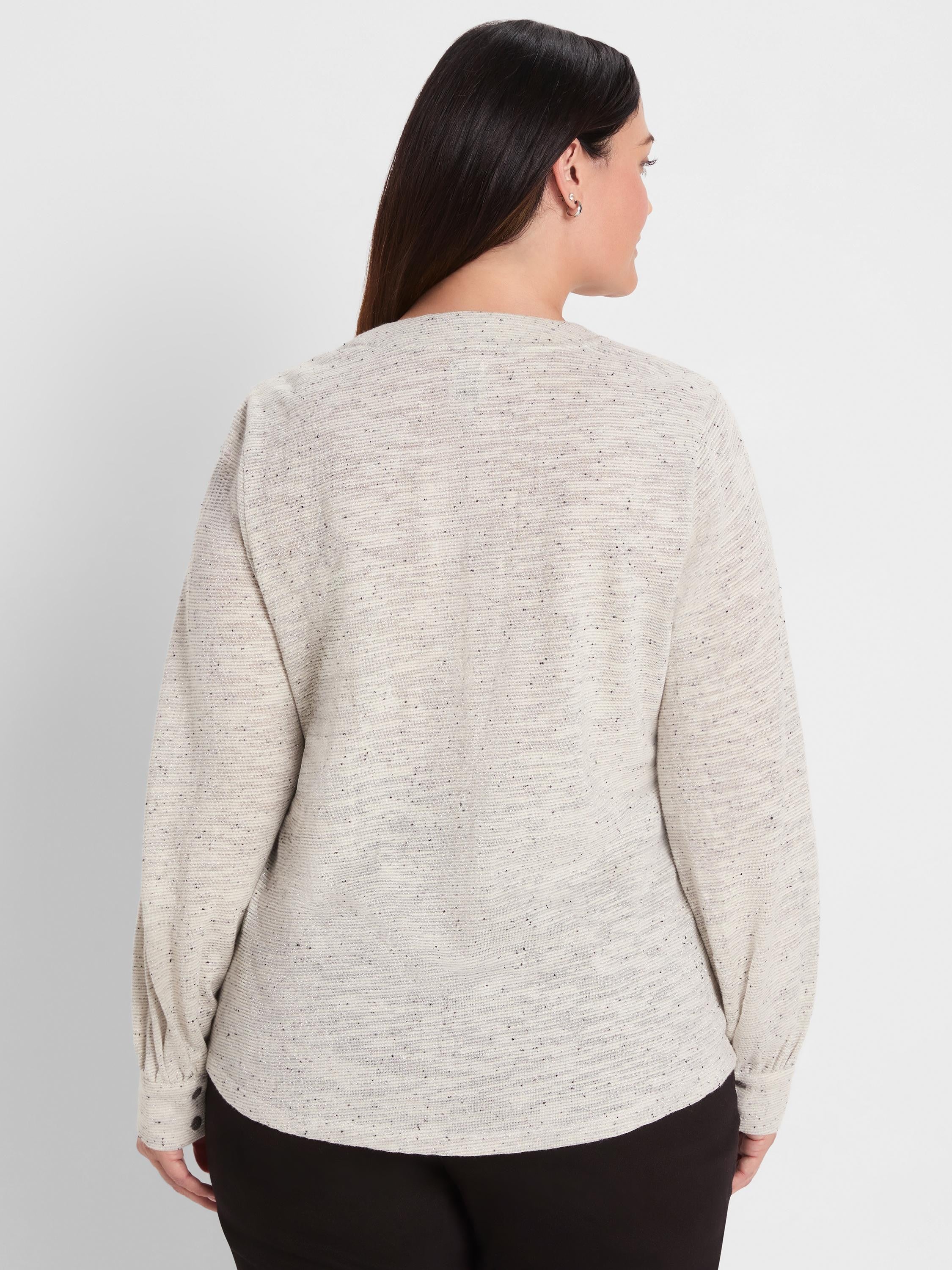 Light beige nep knit top with dark flecks, subtle horizontal ribbing, and metallic shimmer. Long sleeves, buttoned cuffs.