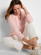 Cream thermal knit top with coral pink horizontal stripes, split V-neck, and long sleeves.