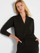 Black V-neck top with gold horizontal sparkle stripes, ribbed texture, and long sleeves.