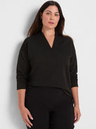 Black top featuring sparkling horizontal stripes, ribbed texture, a notched V-neck, and long sleeves.