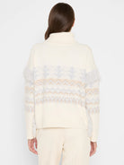 Cream turtleneck sweater with grey & tan fair isle pattern, grey fringe along the sides.