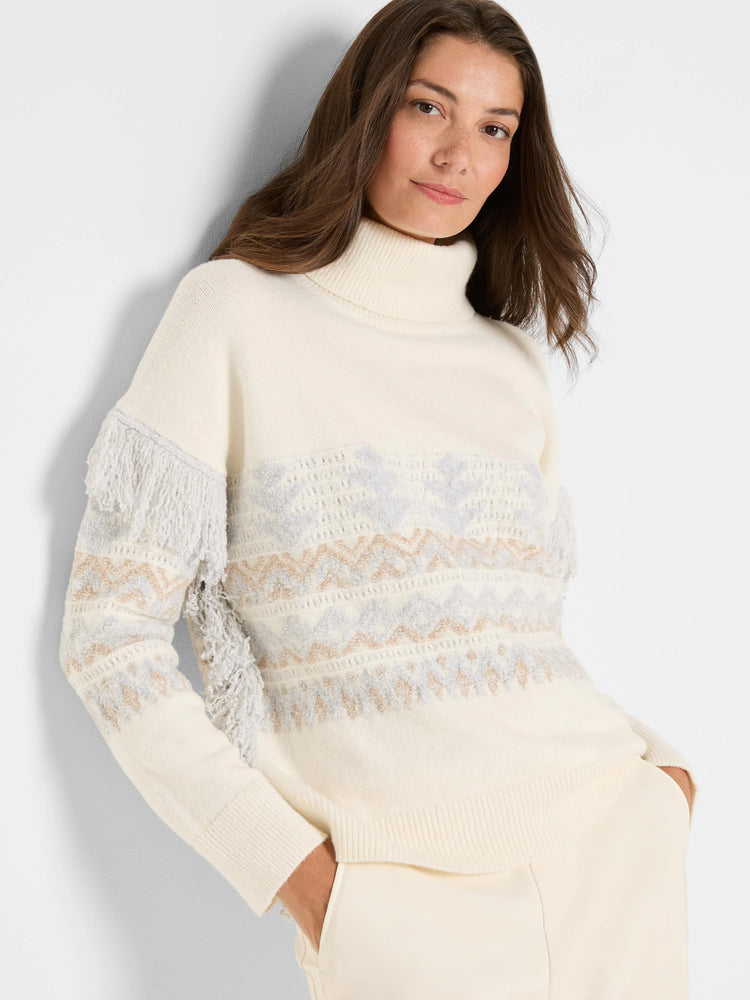 Cream turtleneck sweater with light blue/beige Fair Isle pattern and fringe on upper arms.