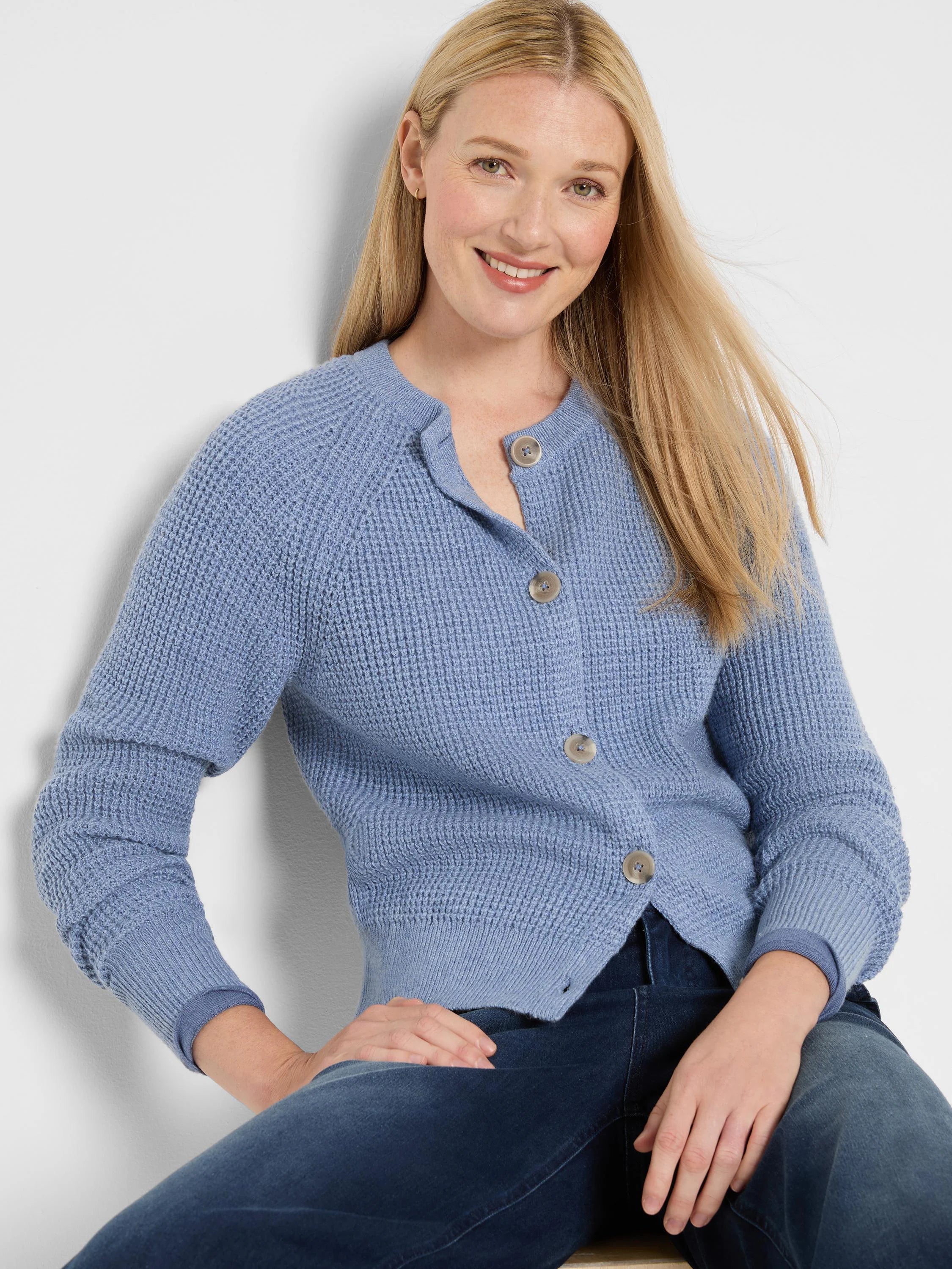 Periwinkle blue waffle knit cardigan with a crew neck and light buttons, shown on a model.