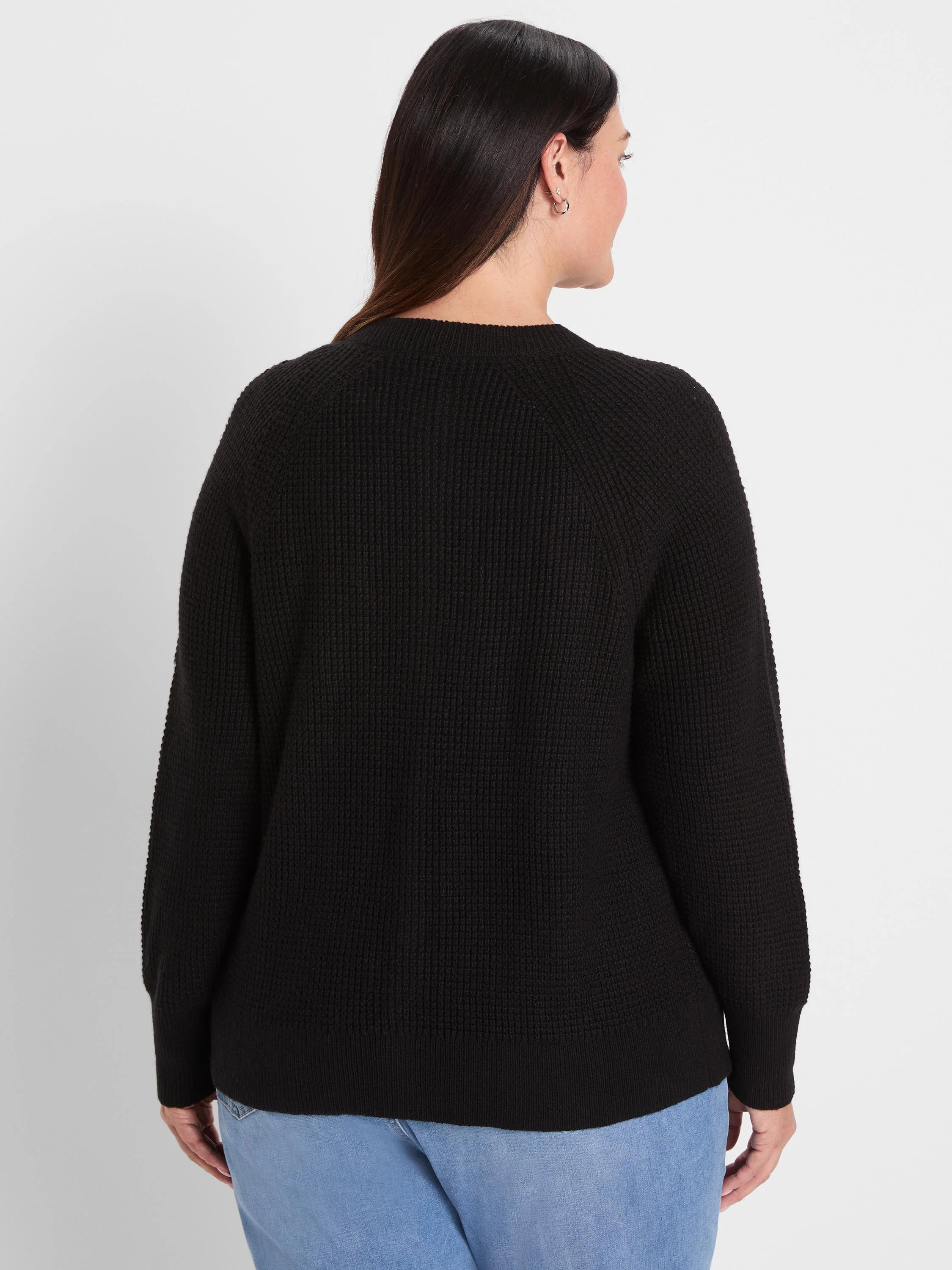 Black waffle-knit cardigan, seen from the back, with long sleeves, ribbed cuffs, and hem.