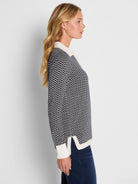 Two-tone black & white jacquard sweater with a geometric pattern. Features a white collar, ribbed cuffs, & side-slit hem.