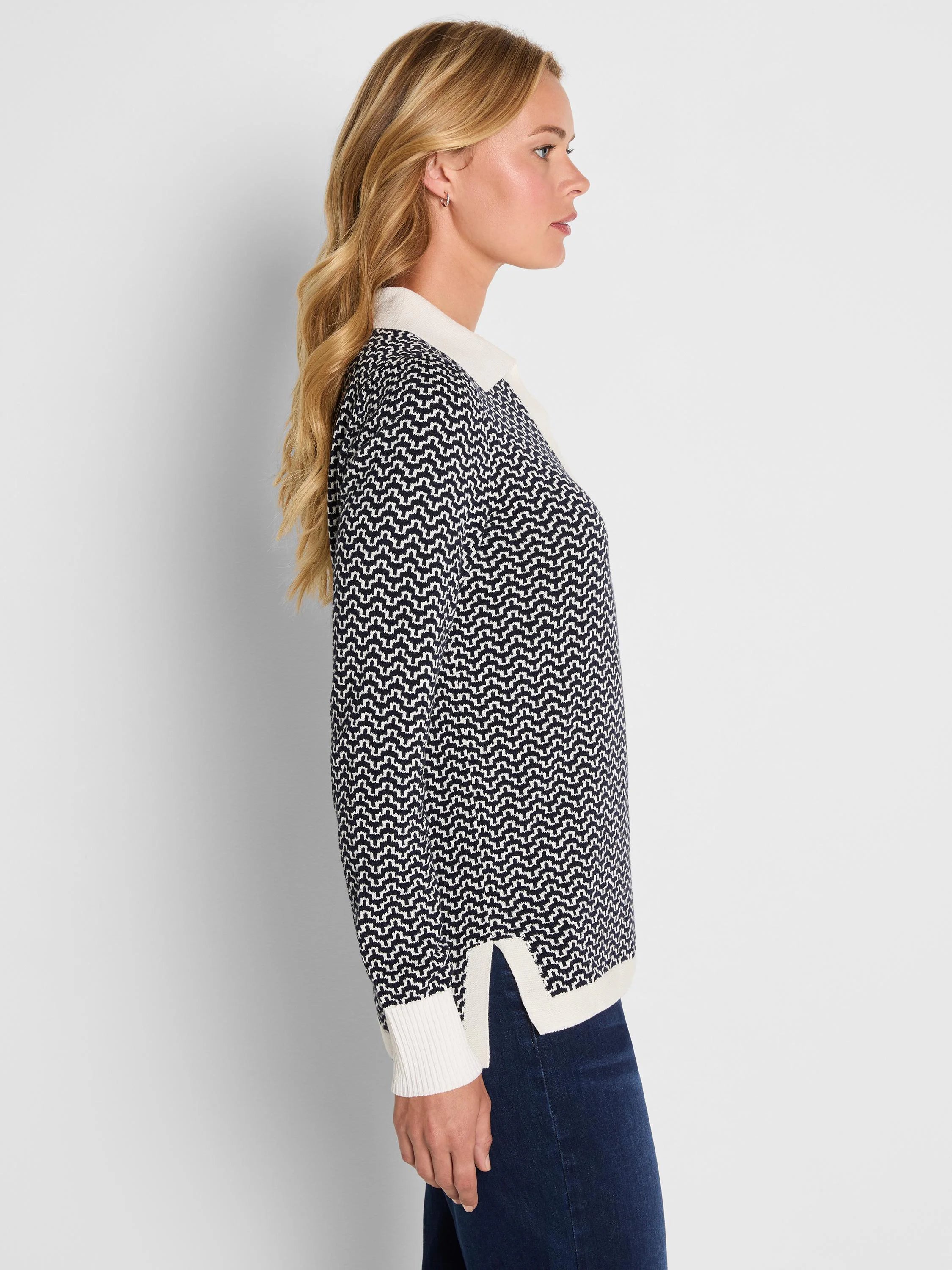 Two-tone black & white jacquard sweater with a geometric pattern. Features a white collar, ribbed cuffs, & side-slit hem.