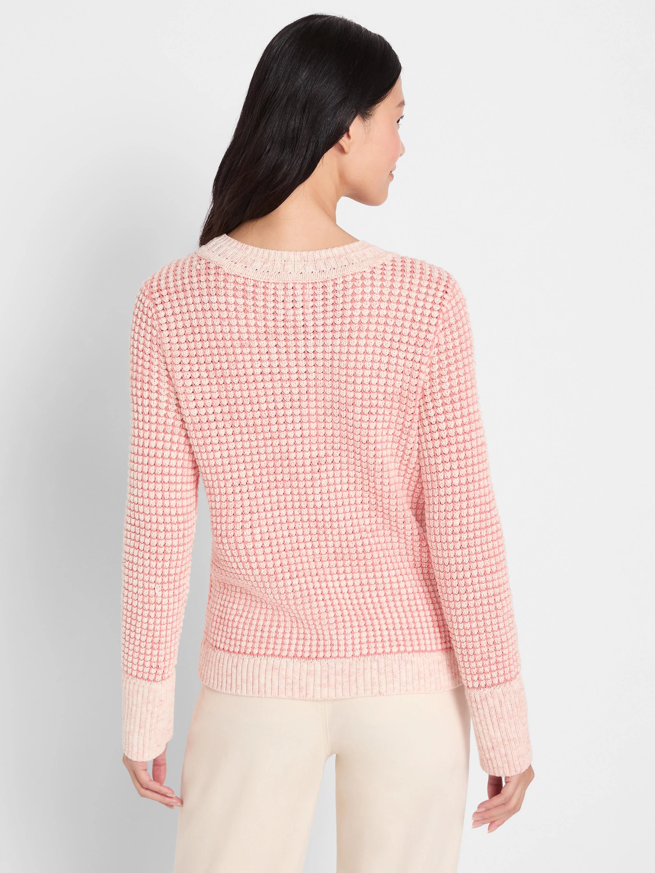 Heathered light pink waffle-knit sweater with off-white ribbed neckline, cuffs, and hem, worn from behind.