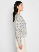 Cream knit jacket with blue and tan textured flecks, gold buttons, and ribbed cuffs and hem.