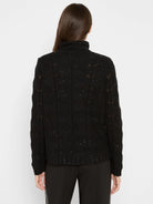 Black cable knit turtleneck sweater with subtle sparkles and openwork patterns, viewed from the back.