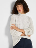 Light gray cable knit turtleneck sweater with wavy patterns and embedded subtle sparkle.