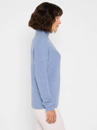 Periwinkle blue waffle-knit turtleneck sweater with a relaxed fit and long sleeves, modeled in profile.