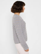 Light grey, fuzzy sweater with an open-knit wavy pattern of small eyelet holes.
