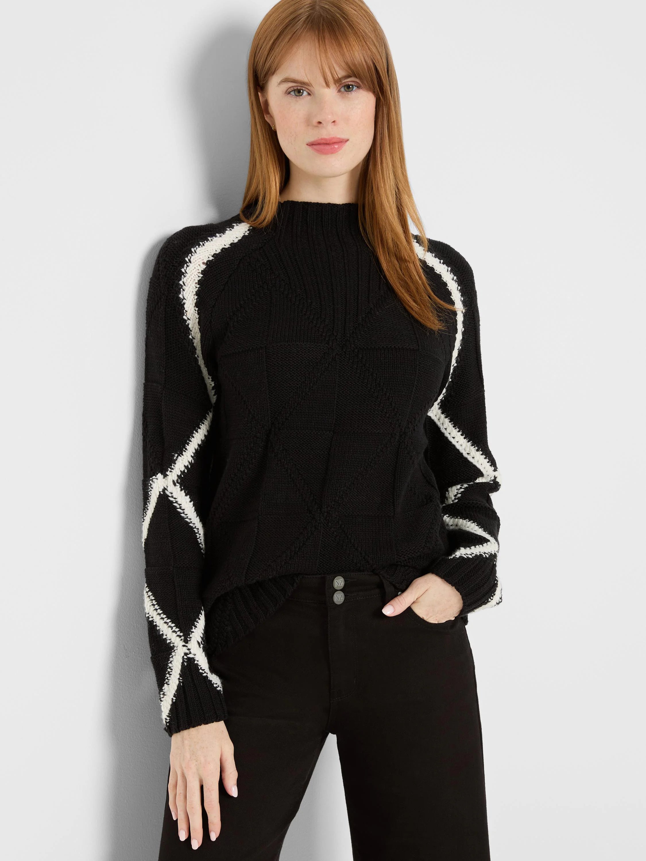 Black mock neck sweater with white diamond patterns on sleeves & shoulders.
