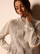 Gray mock-neck sweater with cream arm stripes & knitted diamond patterns. Ribbed collar/cuffs.
