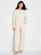 Cream long-sleeve sweater featuring an open-knit paisley dot pattern throughout.