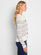 Ivory cardigan with black wavy zig-zag pattern and round brown buttons.