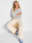 Light cream open-knit V-neck sweater with blue striped collar and cuffs.