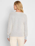 Back of a cream sweater with blue tuck texture. Features blue striped cuffs and a blue trim on the back neckline.