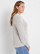 Cream & blue speckled open knit sweater with a textured weave and blue striped cuffs.