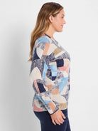 Women's crewneck sweater with abstract geometric pattern in navy, light blue, cream, peach, and tan.