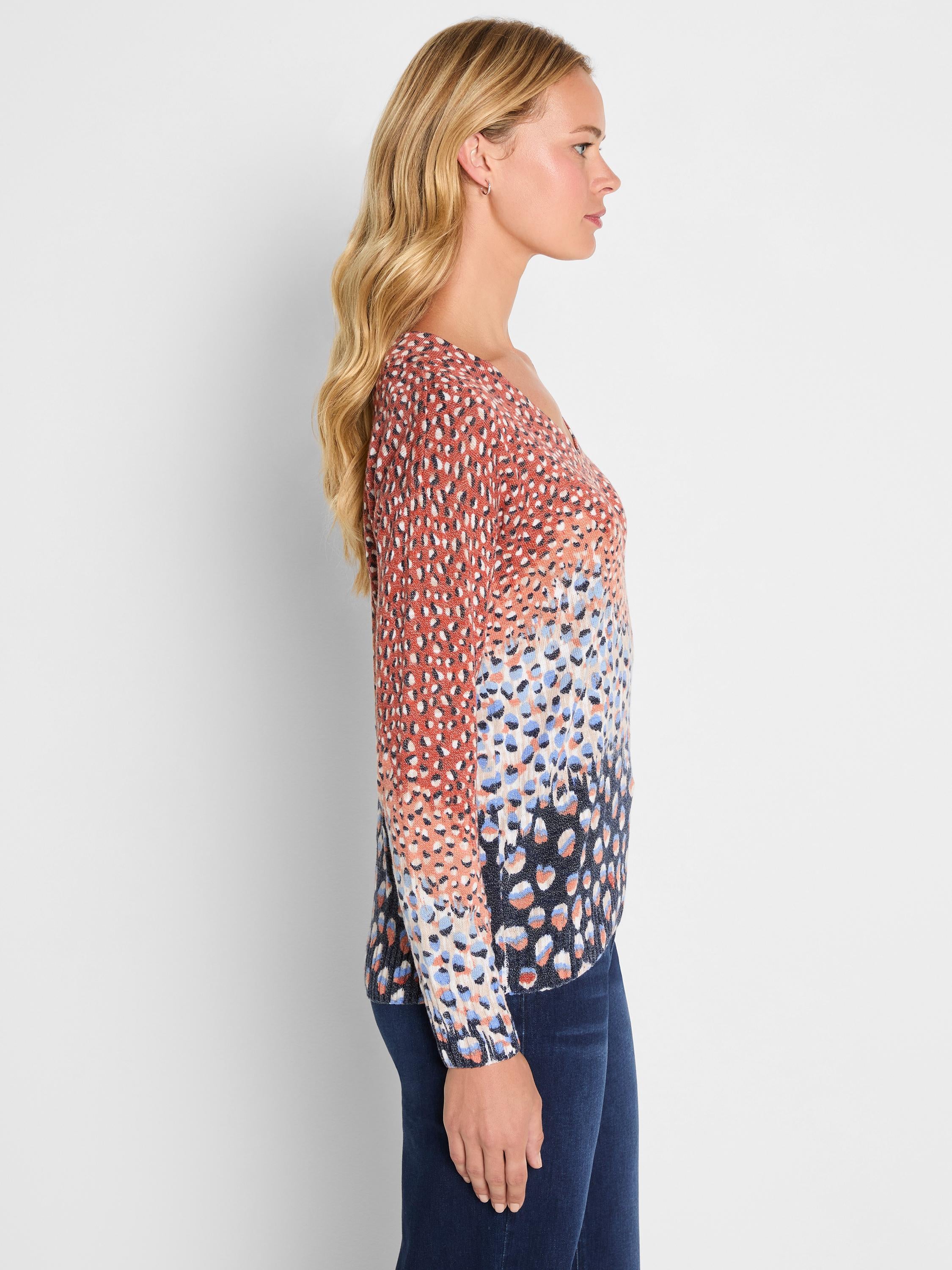 A fitted V-neck sweater in a colorful spotted print that fades from rust and cream to dark navy on the hem.