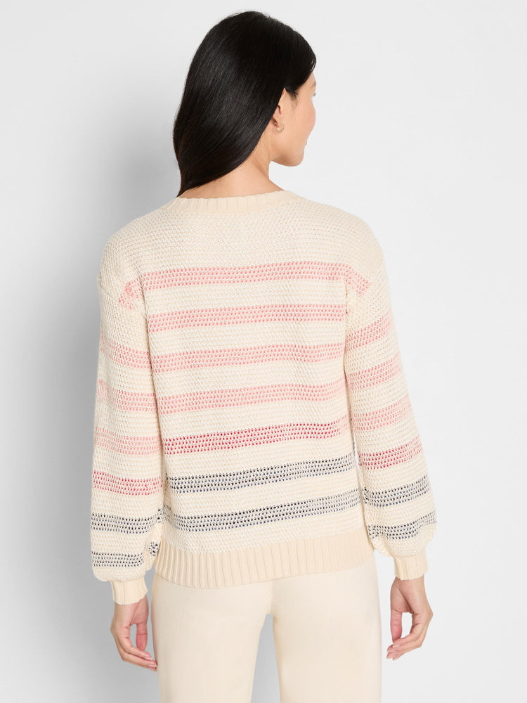 The model wears a cream open-knit sweater with multicolor stripes and relaxed balloon sleeves.
