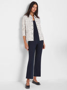 Cream knit jacket with black neps, metal grommets, and frayed edges on collar, placket, and hem.