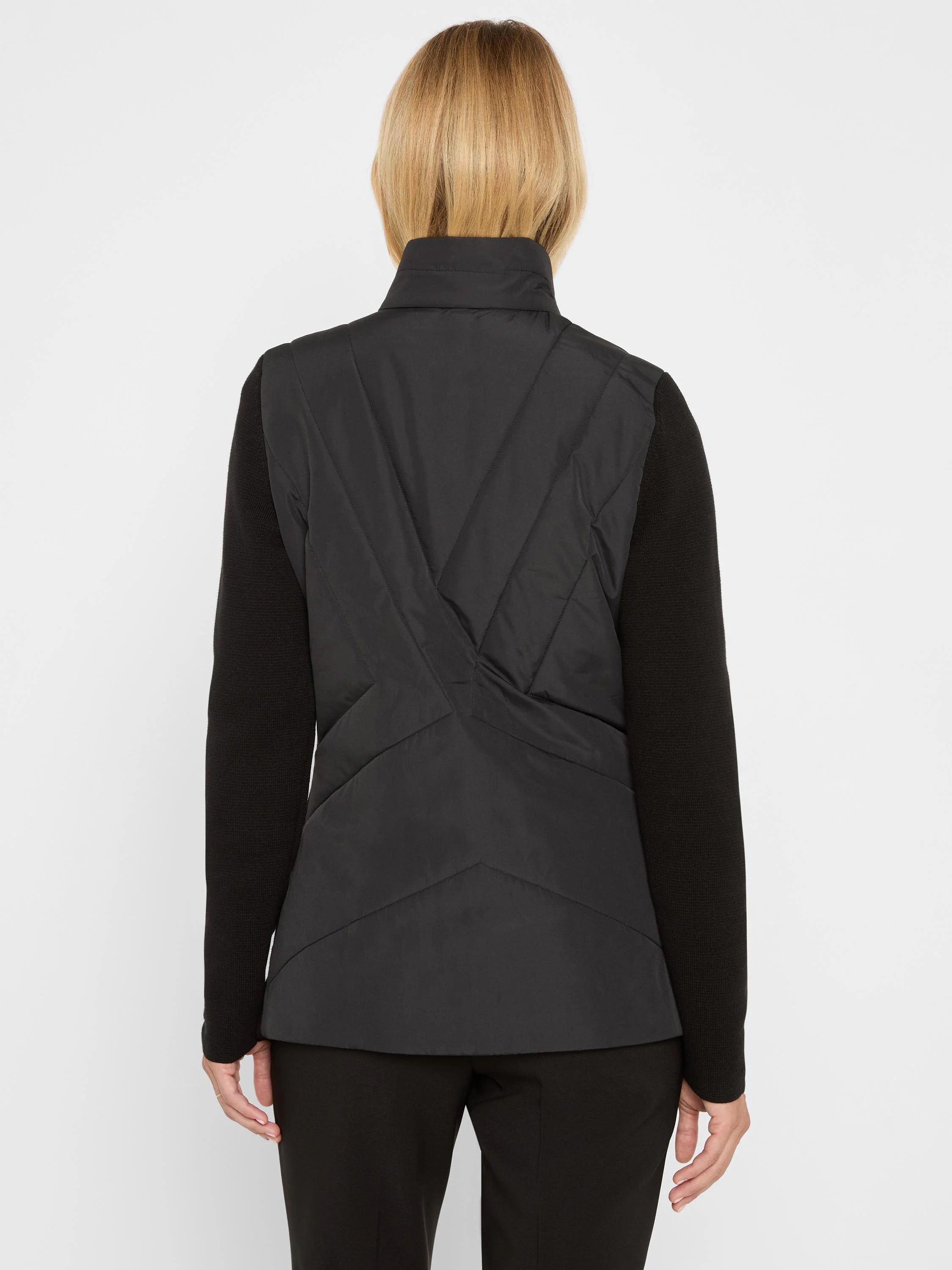 Black blazer, back view: high collar, padded back with geometric stitching, ribbed knit sleeves.