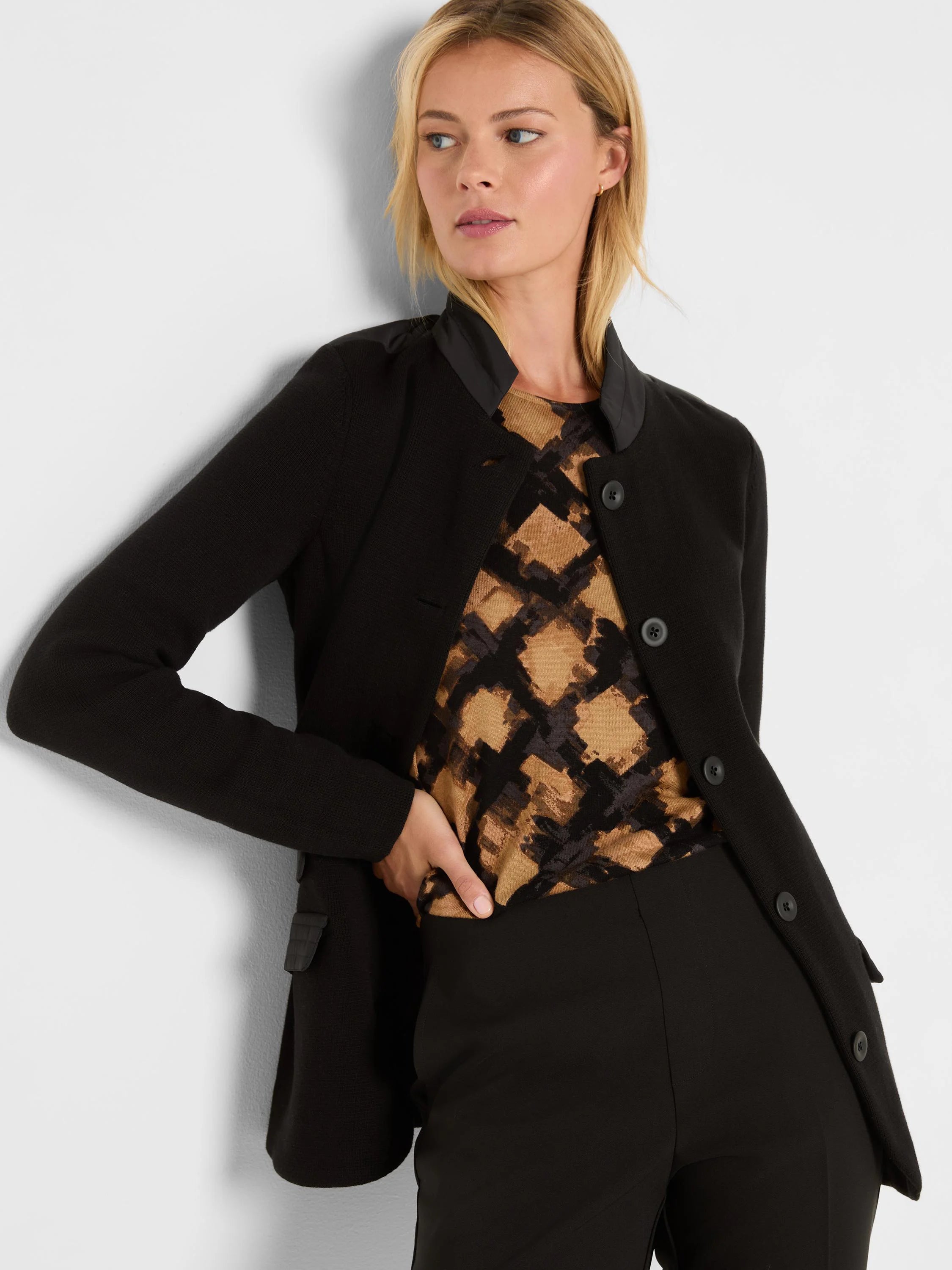 Black knit blazer with a standing contrast collar and three dark front buttons.