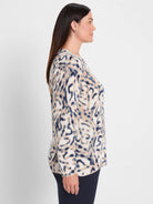 Long-sleeve sweater with a blurry leaf-like pattern of dark blue and tan shapes on a cream background.
