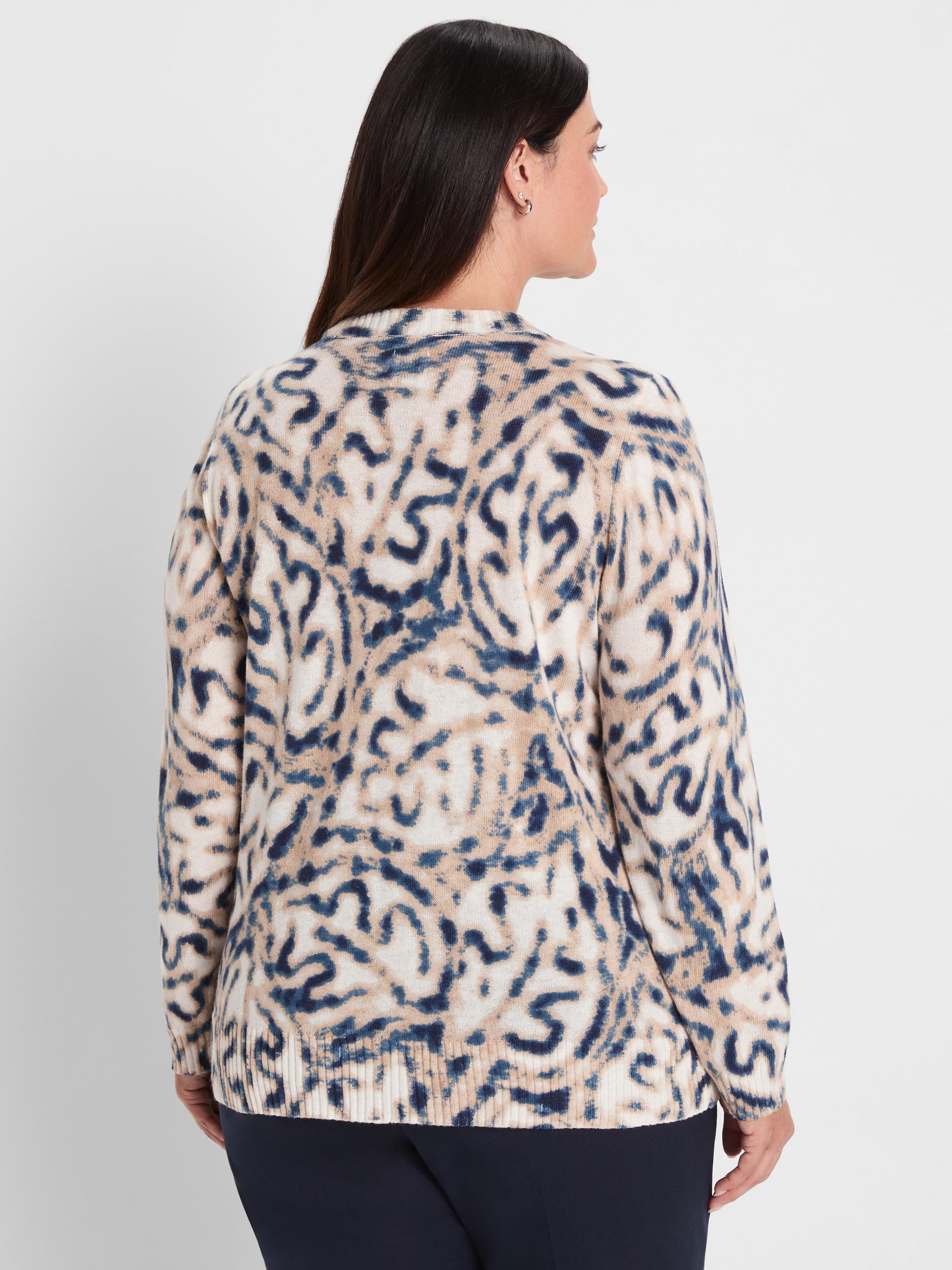Cream sweater featuring a blurry, organic pattern in dark blue and tan. Model wears it from behind.