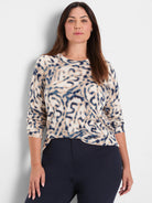 Cream sweater with blue and tan blurry leaf pattern, crew neck, long sleeves.