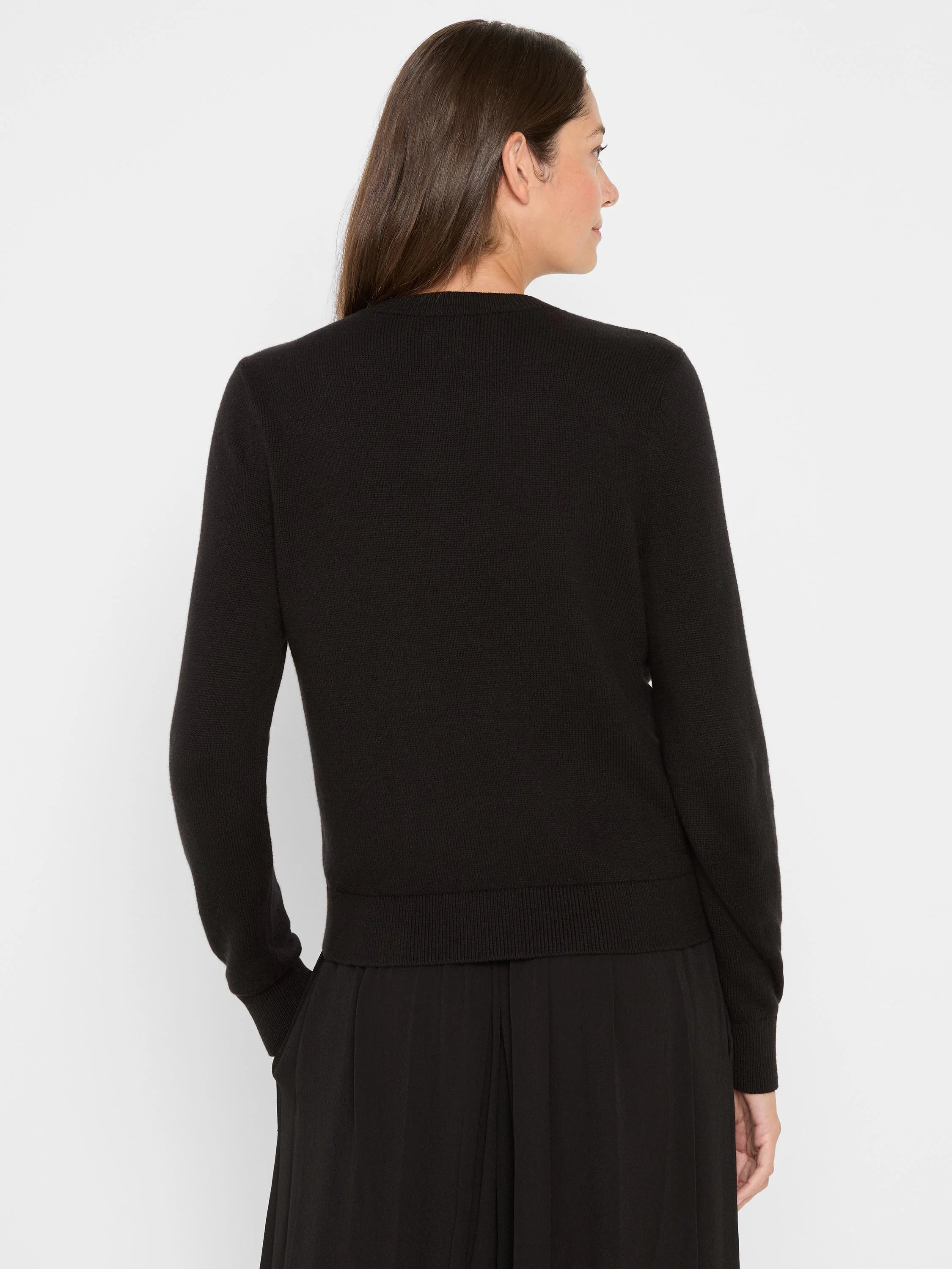Back view of a plain black knit cardigan with ribbed cuffs and hem.
