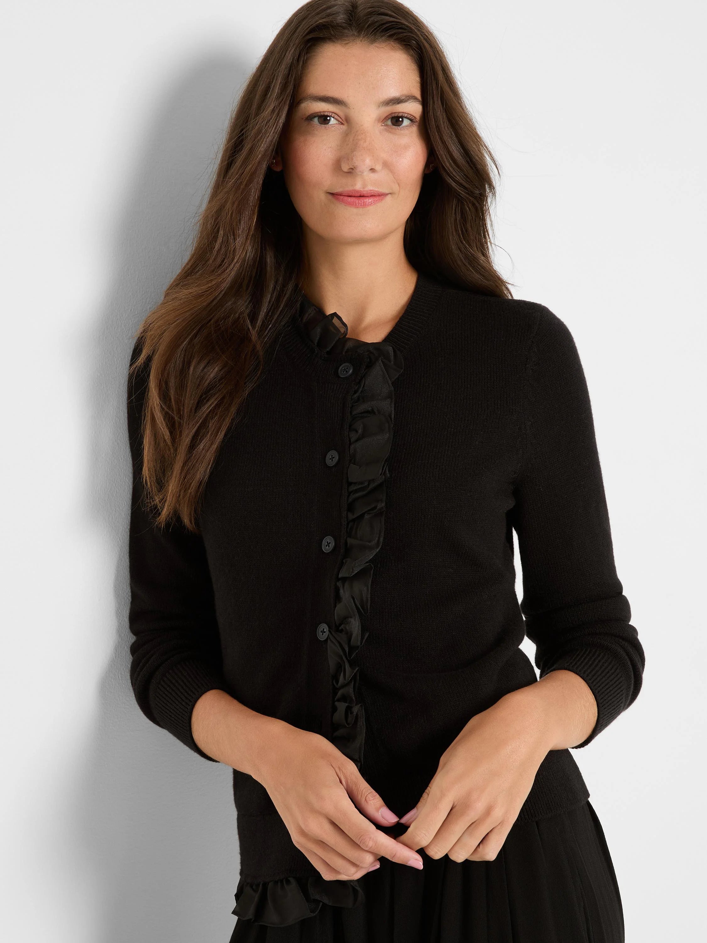 Black knit cardigan with satin ruffle front, button placket, round neck, and long sleeves.