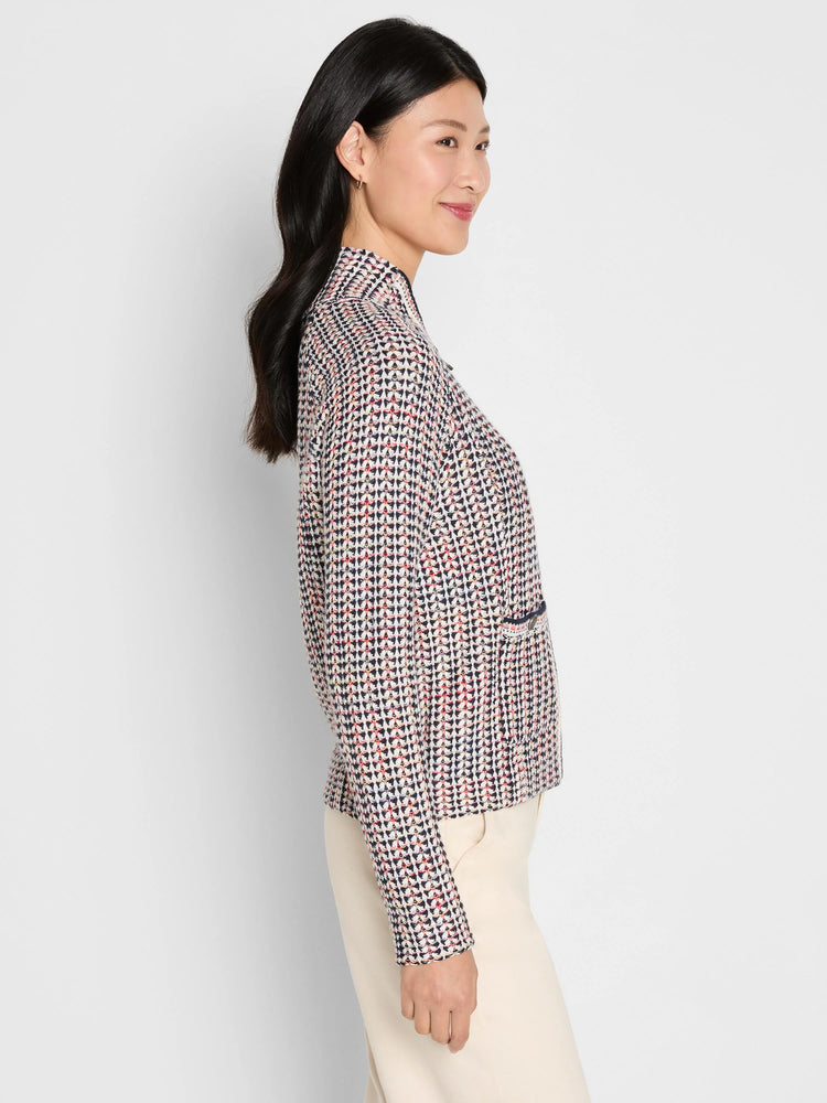 Tuck stitch jacket with cream, navy, red, and yellow woven pattern. Features a stand collar and patch pocket.