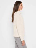 Cream V-neck shaker stitch sweater with long sleeves, featuring a visible ribbed texture.