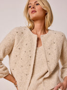 Light beige textured knit tank with subtle metallic flecks, worn under a matching open cardigan embellished with silver...