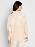 Light beige cardigan with white embroidered floral patterns on back and sleeves. Ribbed mock neck and cuffs.