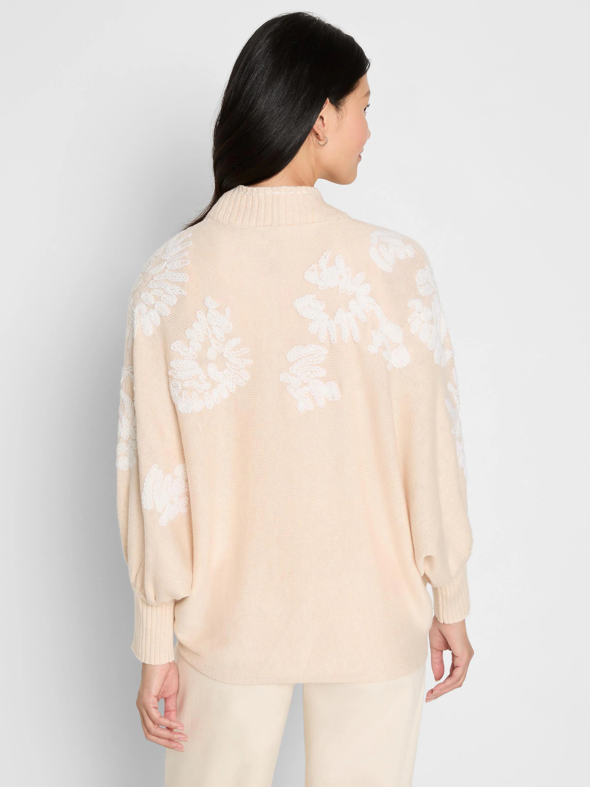 Light beige cardigan with white embroidered floral patterns on back and sleeves. Ribbed mock neck and cuffs.
